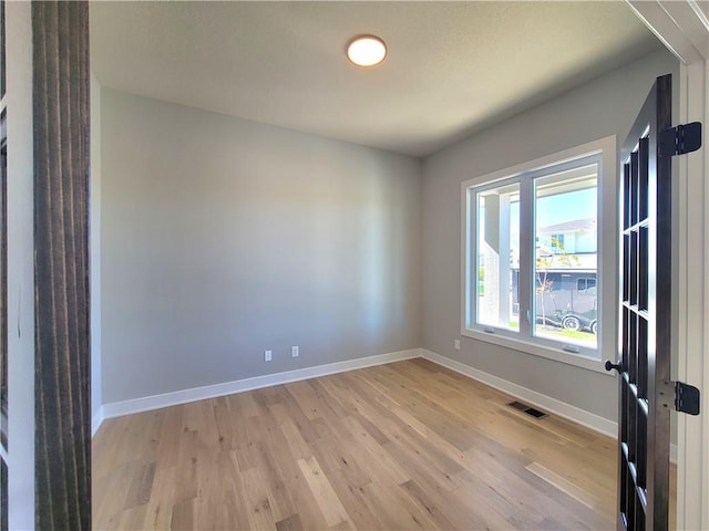 spare room with visible vents, baseboards, and light wood finished floors