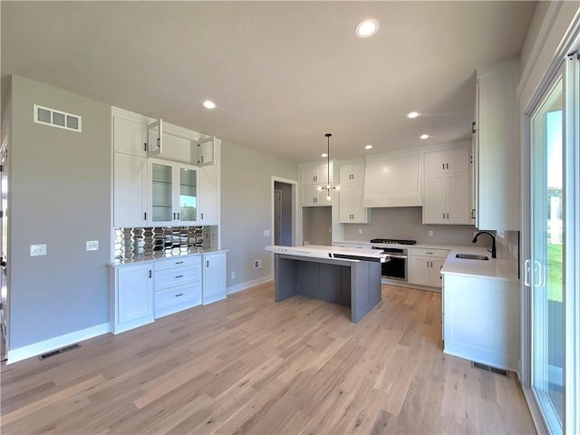 kitchen featuring a sink, a center island, backsplash, and visible vents