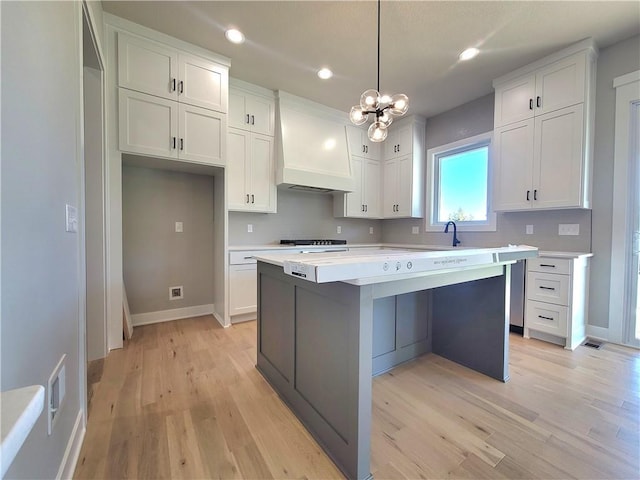 kitchen featuring decorative backsplash, a kitchen island, light countertops, custom exhaust hood, and white cabinetry