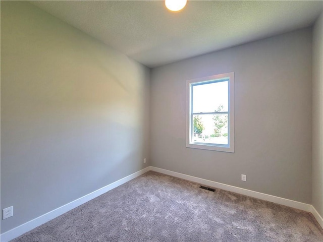 spare room with light colored carpet, baseboards, and visible vents