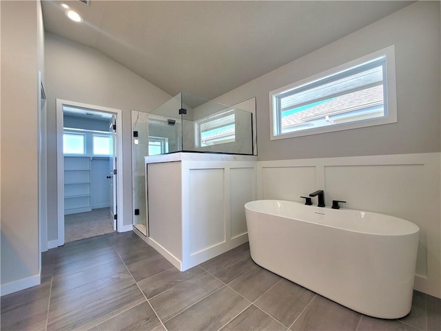 bathroom with a walk in shower, a freestanding tub, a spacious closet, and a healthy amount of sunlight