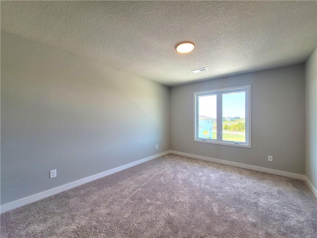 spare room with baseboards, light carpet, a textured ceiling, and visible vents