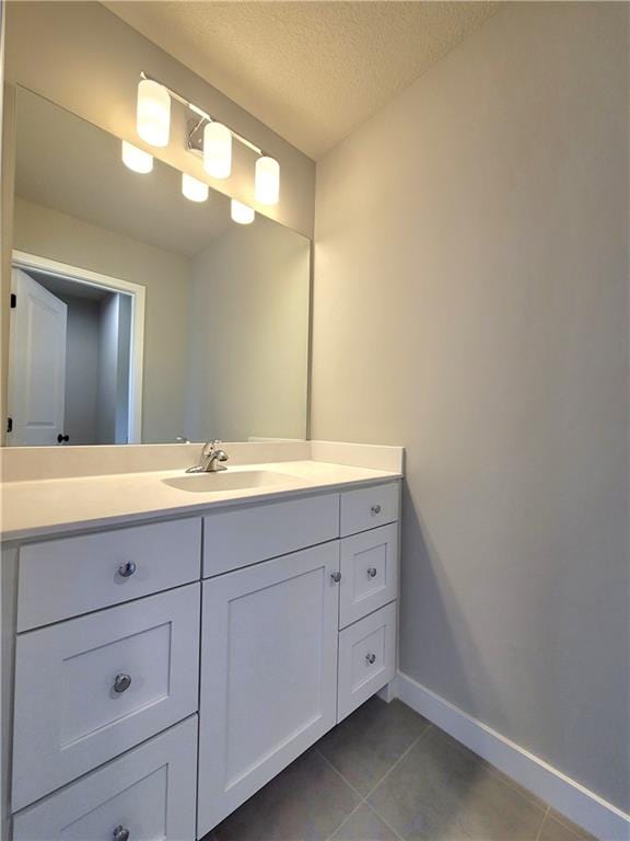 bathroom featuring a textured ceiling, tile patterned flooring, vanity, and baseboards