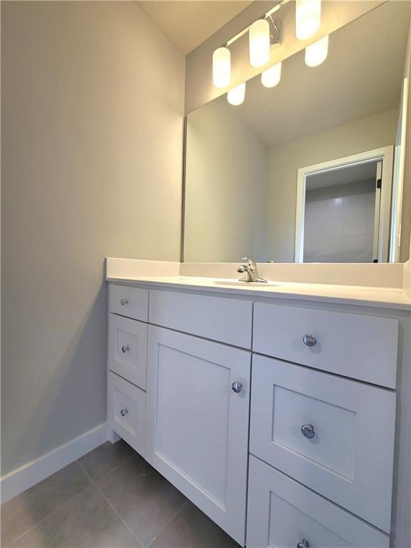 bathroom with baseboards, tile patterned flooring, and vanity