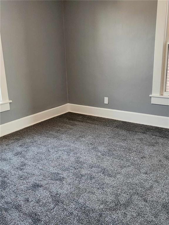 empty room featuring carpet and baseboards