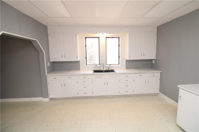 kitchen featuring light countertops, white cabinets, and a sink