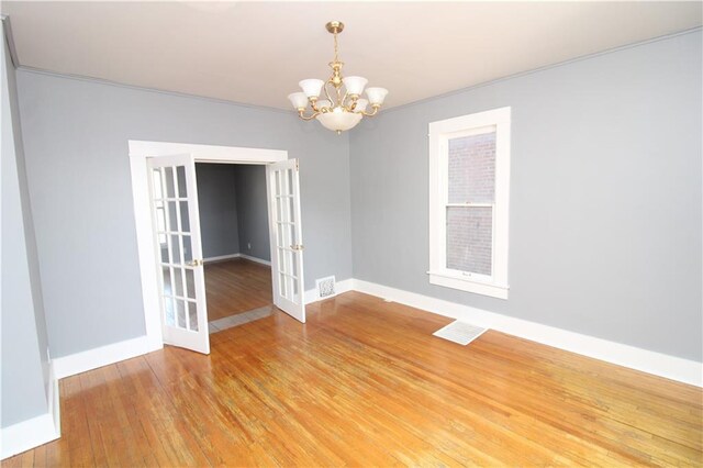 empty room with light wood-type flooring, visible vents, french doors, an inviting chandelier, and baseboards