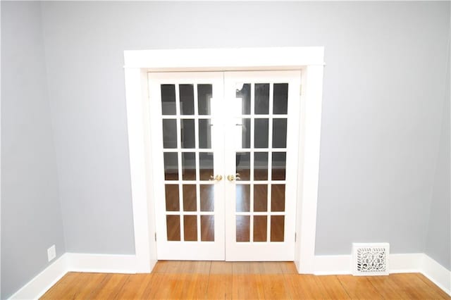 room details with visible vents, baseboards, wood finished floors, and french doors