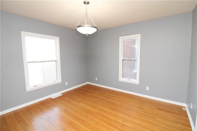 empty room featuring visible vents, baseboards, and light wood-style floors