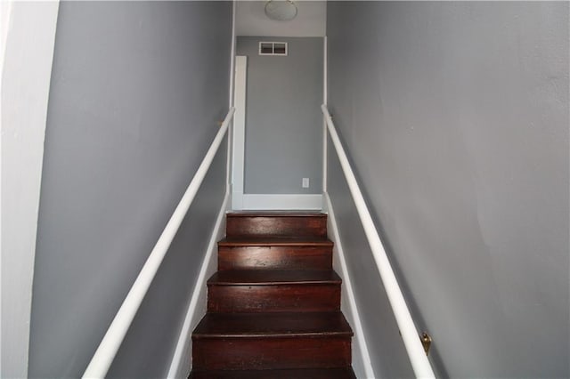 stairway featuring wood finished floors and visible vents