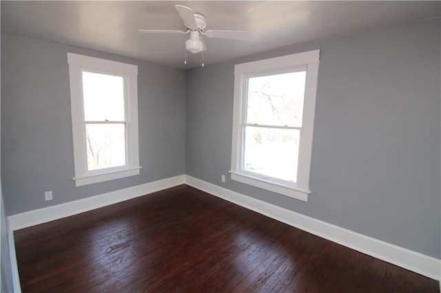 spare room with dark wood finished floors, a healthy amount of sunlight, and baseboards