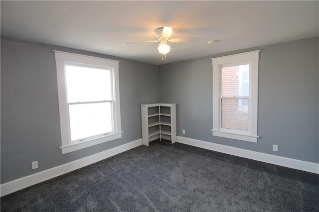 unfurnished room featuring baseboards, ceiling fan, and dark carpet