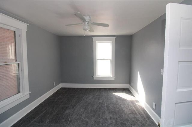 empty room featuring a ceiling fan, baseboards, and dark colored carpet