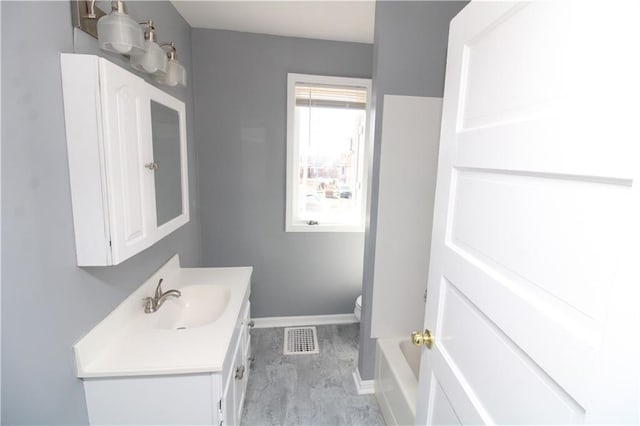 bathroom with visible vents, toilet, vanity, and baseboards