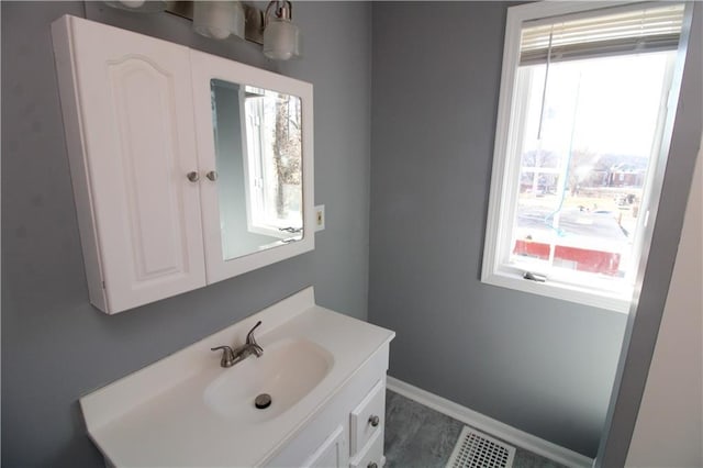 bathroom featuring vanity, visible vents, baseboards, and a wealth of natural light