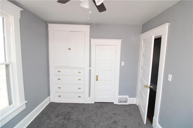 unfurnished bedroom featuring a ceiling fan, baseboards, visible vents, and dark carpet