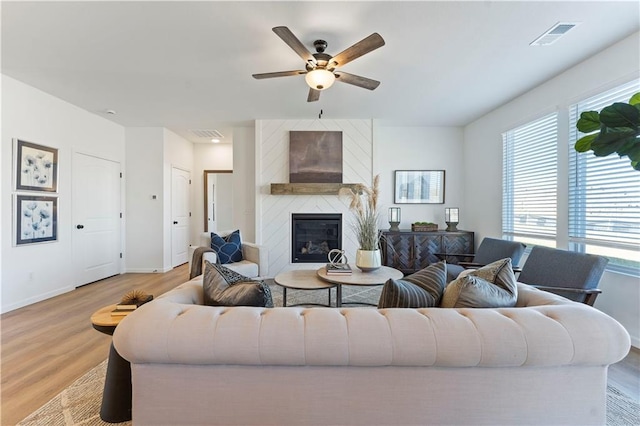 living room featuring ceiling fan, a fireplace, and light hardwood / wood-style floors