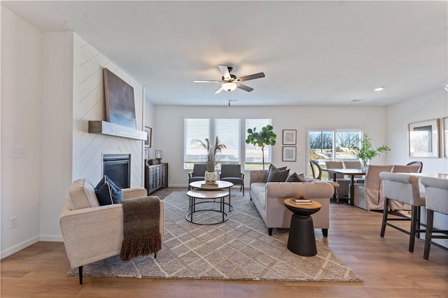 living room with wood-type flooring, ceiling fan, and a fireplace