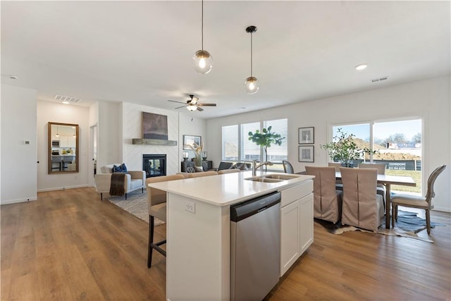 kitchen with pendant lighting, sink, dishwasher, white cabinetry, and a kitchen island with sink