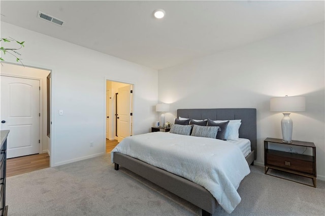 bedroom with connected bathroom and light colored carpet