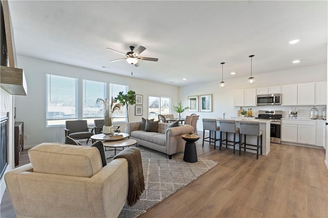 living room with plenty of natural light, ceiling fan, and light hardwood / wood-style flooring