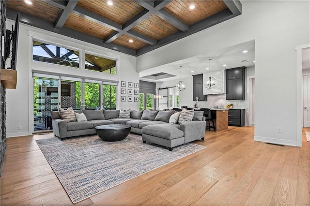 living room featuring coffered ceiling, wood ceiling, an inviting chandelier, light wood-type flooring, and beamed ceiling