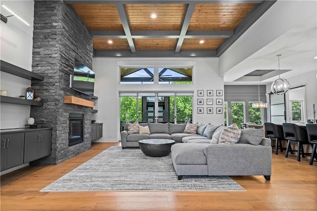 living room featuring coffered ceiling, a stone fireplace, wooden ceiling, light hardwood / wood-style floors, and beam ceiling