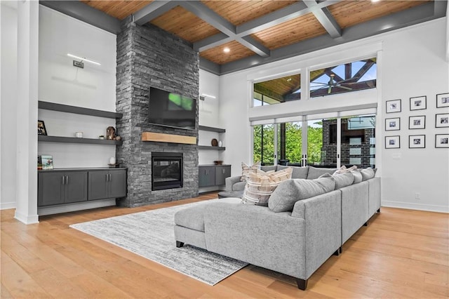 living room featuring a fireplace, beam ceiling, light hardwood / wood-style floors, and wood ceiling