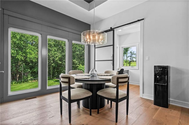 dining room with light hardwood / wood-style flooring, a barn door, and a chandelier