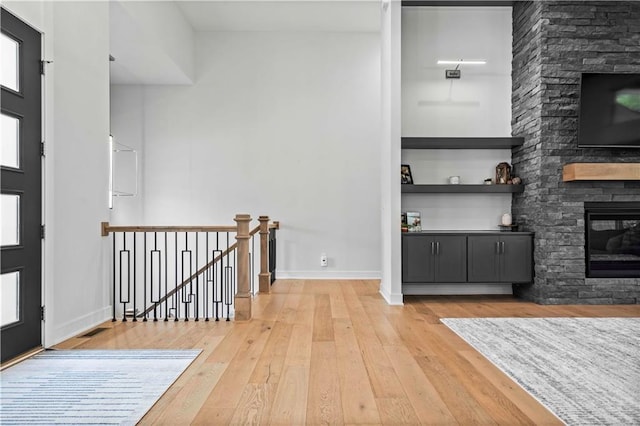 foyer entrance featuring a stone fireplace and wood-type flooring