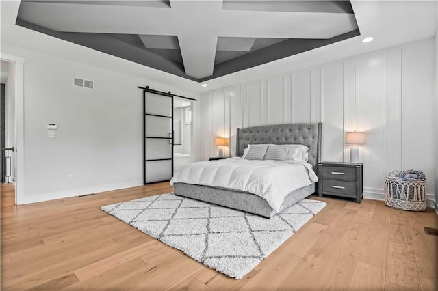 bedroom featuring light hardwood / wood-style floors and a barn door