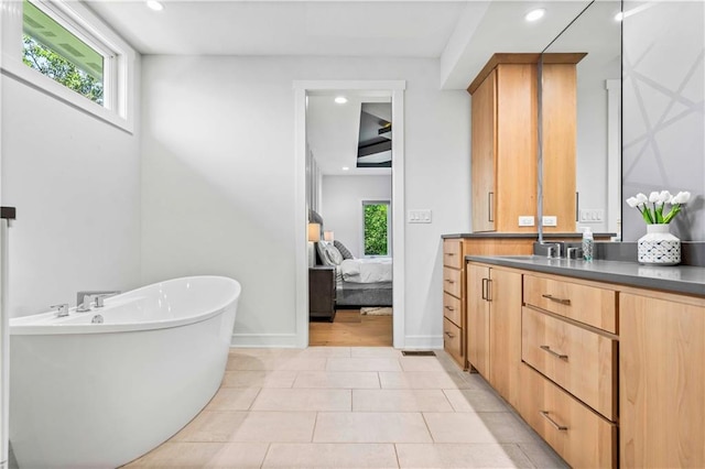 bathroom with a washtub, tile patterned flooring, and vanity