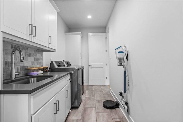 clothes washing area with washer and dryer, cabinets, and sink