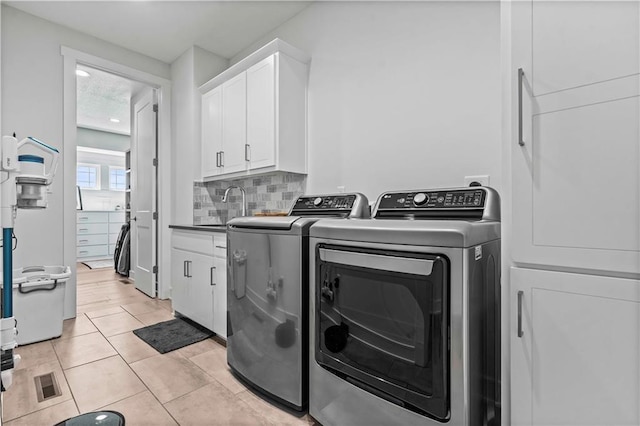 laundry room with washer and dryer, cabinets, light tile patterned floors, and sink