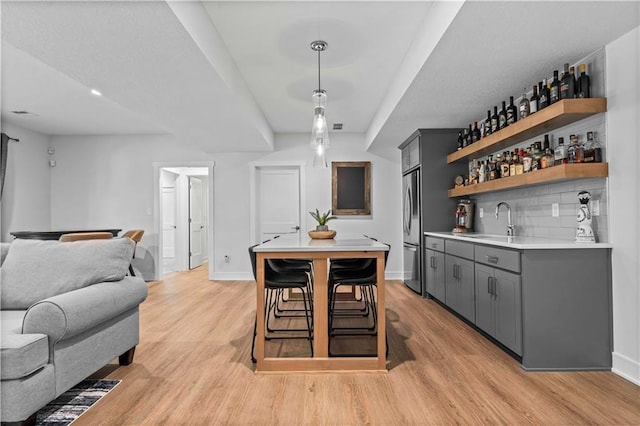 interior space featuring sink, a kitchen breakfast bar, light hardwood / wood-style floors, stainless steel refrigerator, and gray cabinets