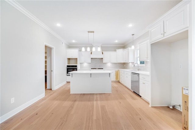 kitchen with stainless steel appliances, a center island, pendant lighting, white cabinetry, and light hardwood / wood-style floors