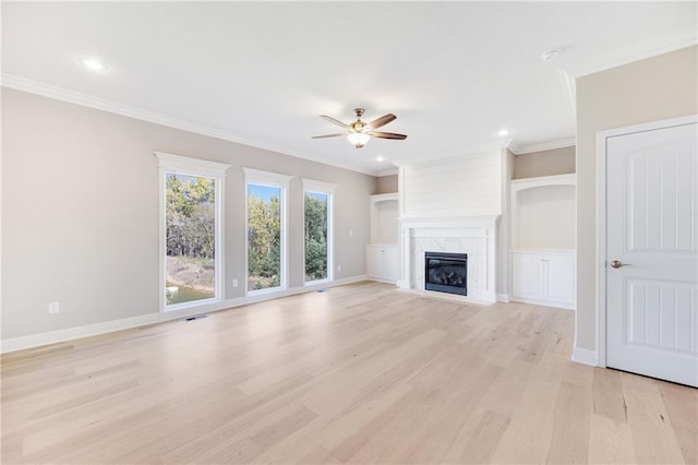 unfurnished living room featuring ceiling fan, light hardwood / wood-style flooring, a premium fireplace, and crown molding