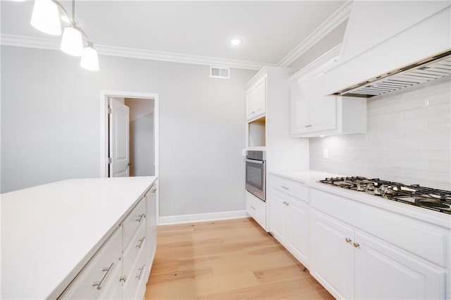 kitchen with gas cooktop, hanging light fixtures, premium range hood, white cabinets, and oven