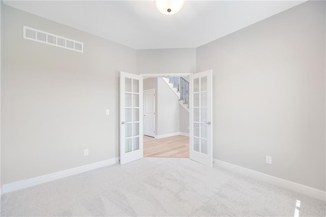 unfurnished room featuring light carpet and french doors