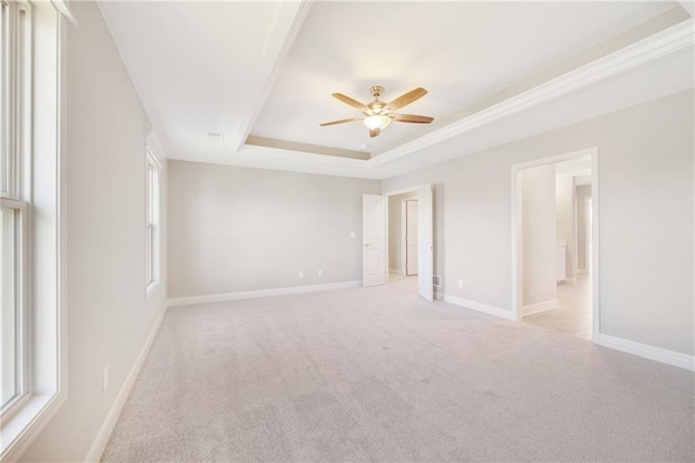 unfurnished room with ceiling fan, a raised ceiling, and light colored carpet