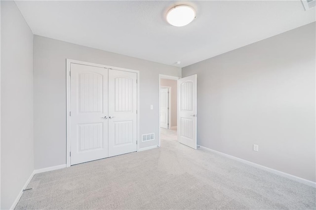 unfurnished bedroom featuring a closet and light colored carpet