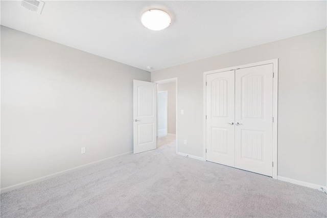 unfurnished bedroom with a closet and light colored carpet