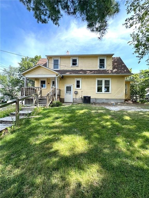 back of property featuring a lawn, a chimney, and central air condition unit