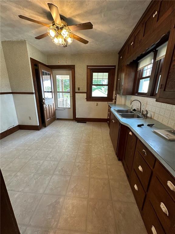 kitchen with dark brown cabinetry, sink, tasteful backsplash, ceiling fan, and light tile floors