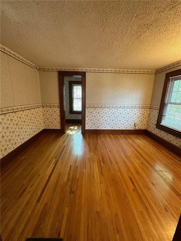 unfurnished room with hardwood / wood-style floors and a textured ceiling