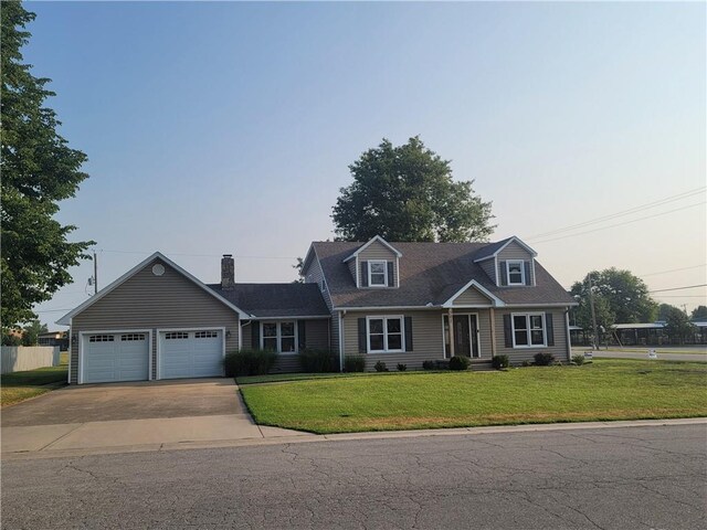 cape cod home featuring a garage and a yard