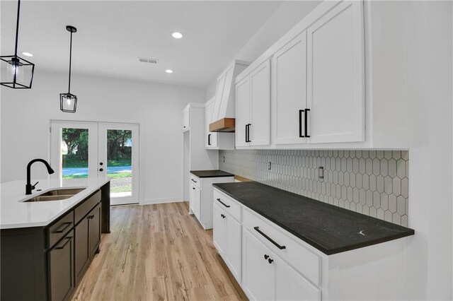 kitchen featuring sink, decorative light fixtures, light hardwood / wood-style flooring, decorative backsplash, and white cabinets