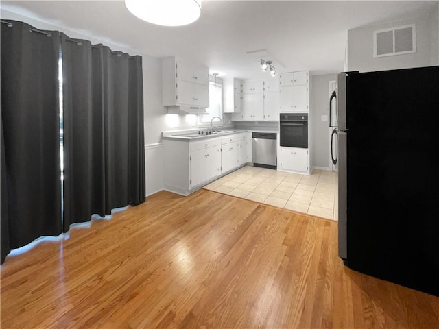 kitchen with white cabinets, black appliances, and light hardwood / wood-style floors