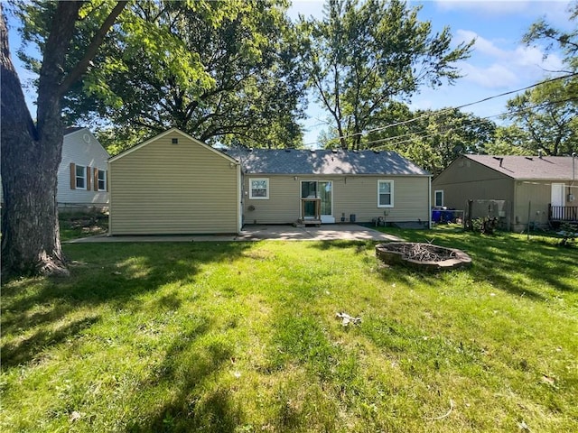 back of property with a yard, a patio, and an outdoor fire pit