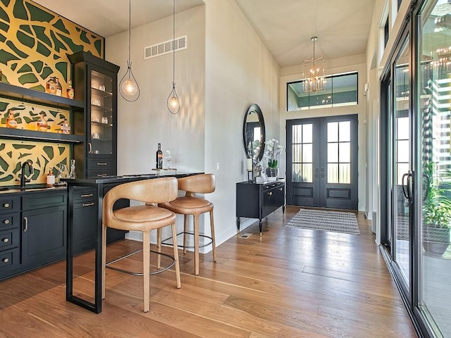 8013 Millridge St, Shawnee, KS 66220 - bar featuring light wood finished floors, visible vents, a sink, indoor wet bar, and a high ceiling